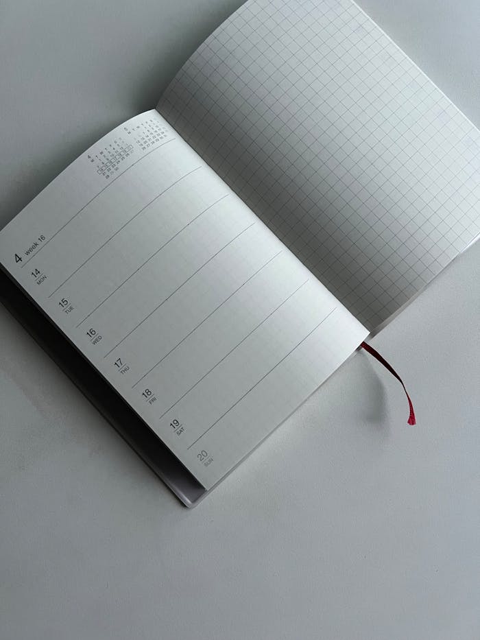 Open planner with calendar and grid pages on a neutral background, highlighting simplicity and organization.