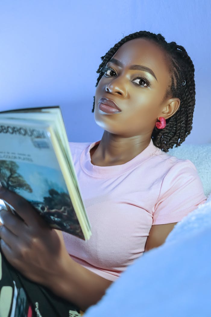 A young woman in a pink shirt reading a book indoors, creating a calm and focused atmosphere.
