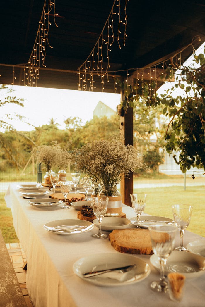 Charming outdoor dining table under string lights, set for a cozy sunset gathering.